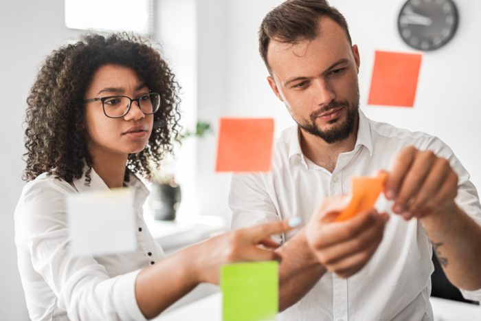 Diverse colleagues sticking notes on wall